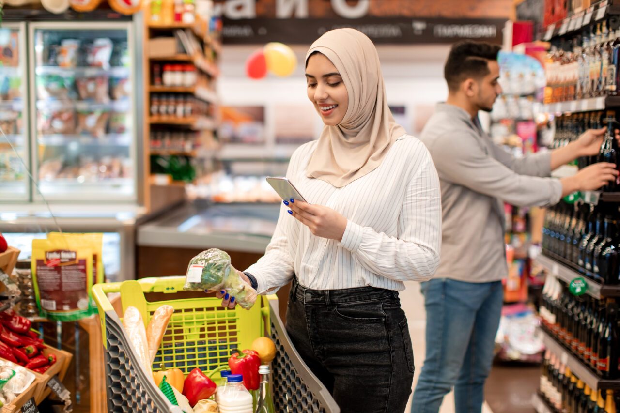 Woman in a hijab using a phone while grocery shopping